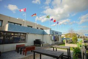Un edificio con varias banderas, mesas al aire libre y un letrero que dice 'Bistrot'.