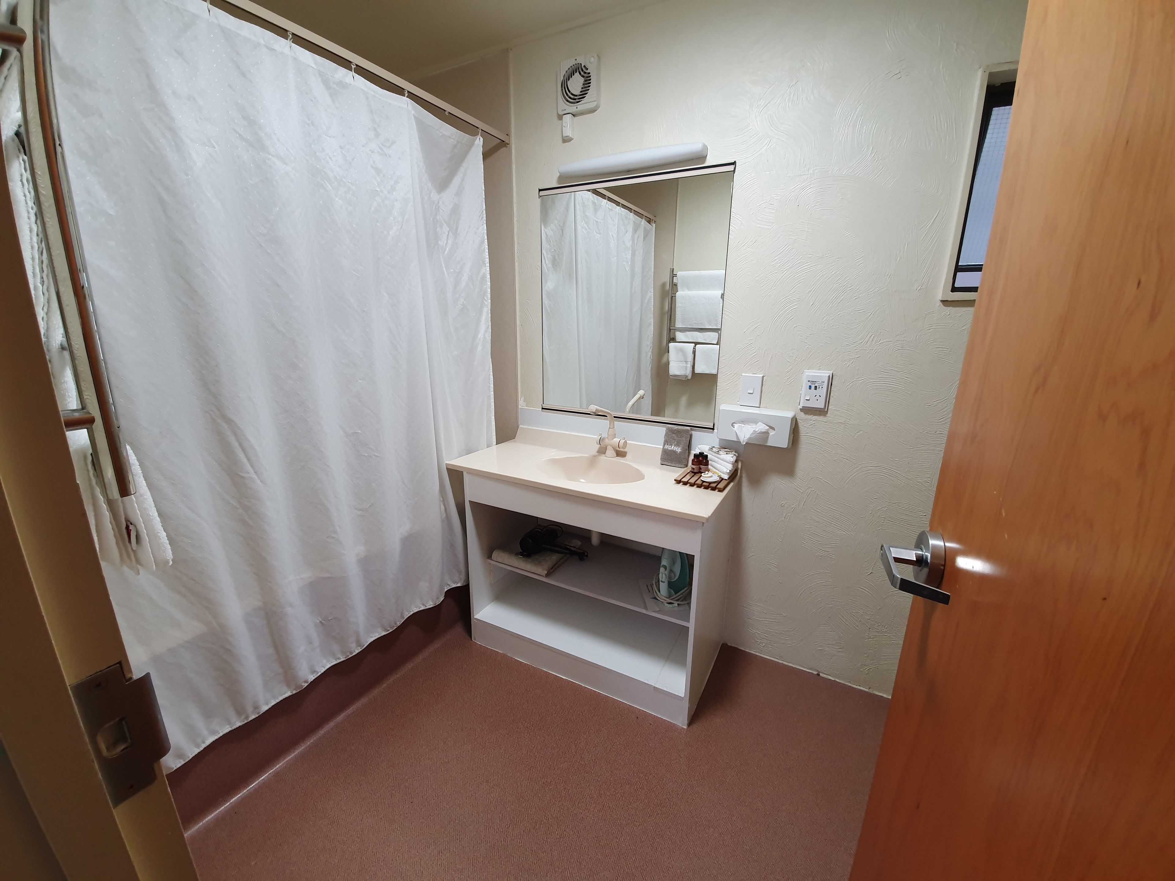 Ein Badezimmer mit weißem Waschbecken, Spiegel und Duschvorhang.