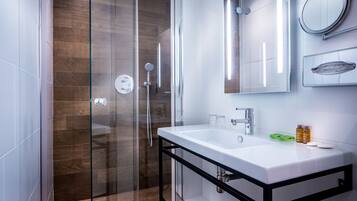 A modern bathroom with a glass shower enclosure, a white sink with a black frame, and a mirror above the sink.