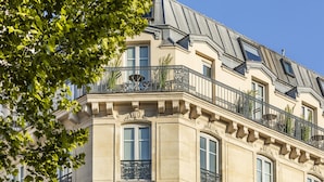 A multi-story building with ornate balconies, large windows, and a classic architectural style. - Hotel Marais Grands Boulevards (Paris)