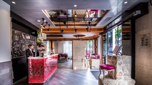 A modern hotel lobby with a reception desk, seating area, and large windows. - Hotel Marais Grands Boulevards (Paris)