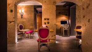 A dining area with stone walls, wooden tables, and chairs. - Hotel Marais Grands Boulevards (Paris)