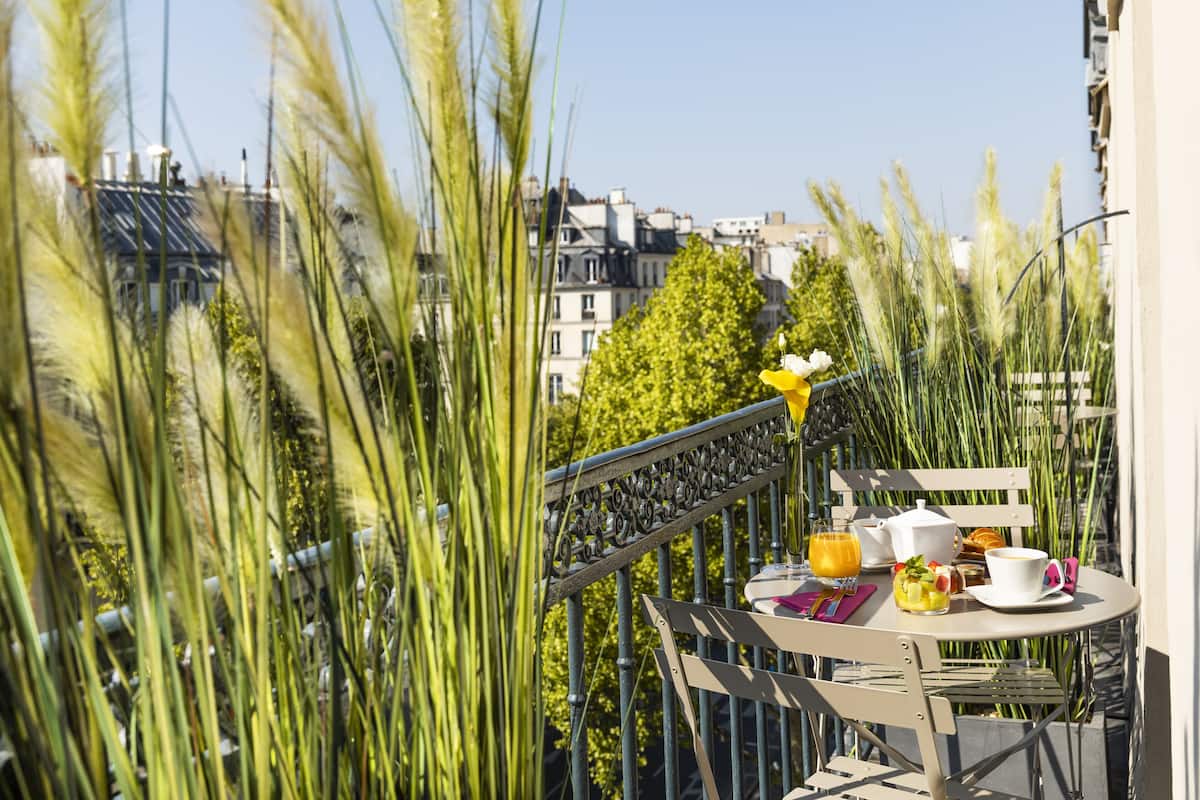 A balcony with a table set for breakfast, overlooking a cityscape.