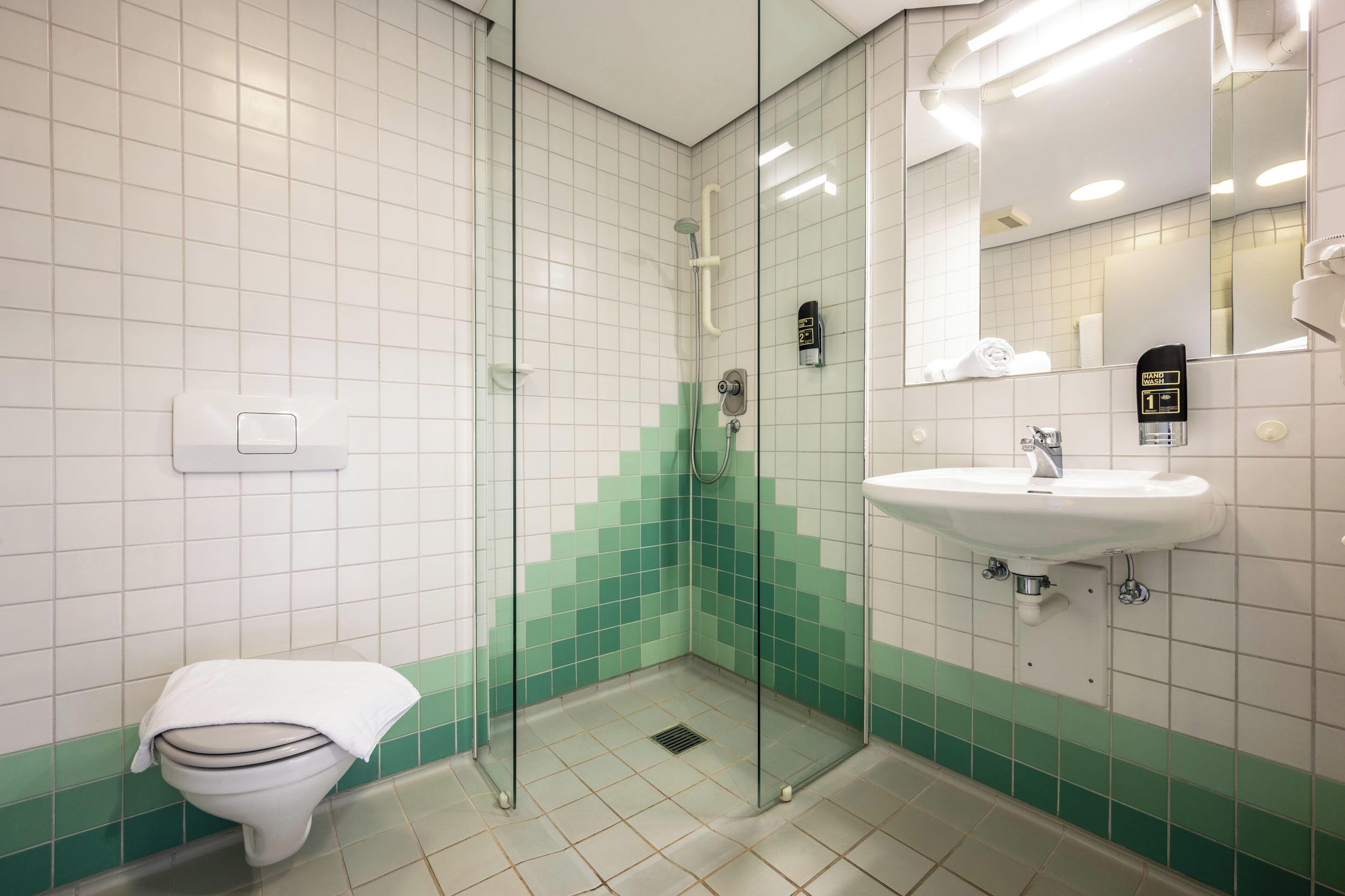 Ein Badezimmer mit Toilette, einer Dusche mit Glastür und einem Waschbecken mit Spiegel.