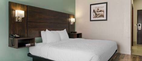 A hotel room with a large bed, two bedside tables with lamps, a telephone, and a framed picture on the wall.