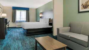 A hotel room with a bed, a sofa, a wooden table, and a desk with a lamp. - Best Western Clare Hotel (Clare)
