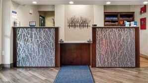 A reception area with two wooden reception desks, a blue mat in front, and a wall-mounted art piece. - Best Western Clare Hotel (Clare)