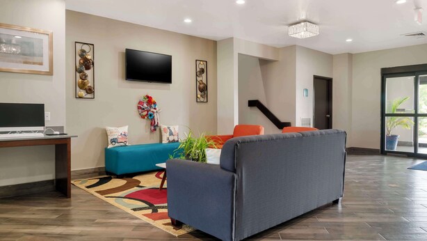 A modern living room with a flat-screen TV, a sofa, a coffee table, and a blue couch. - Best Western Clare Hotel (Clare)