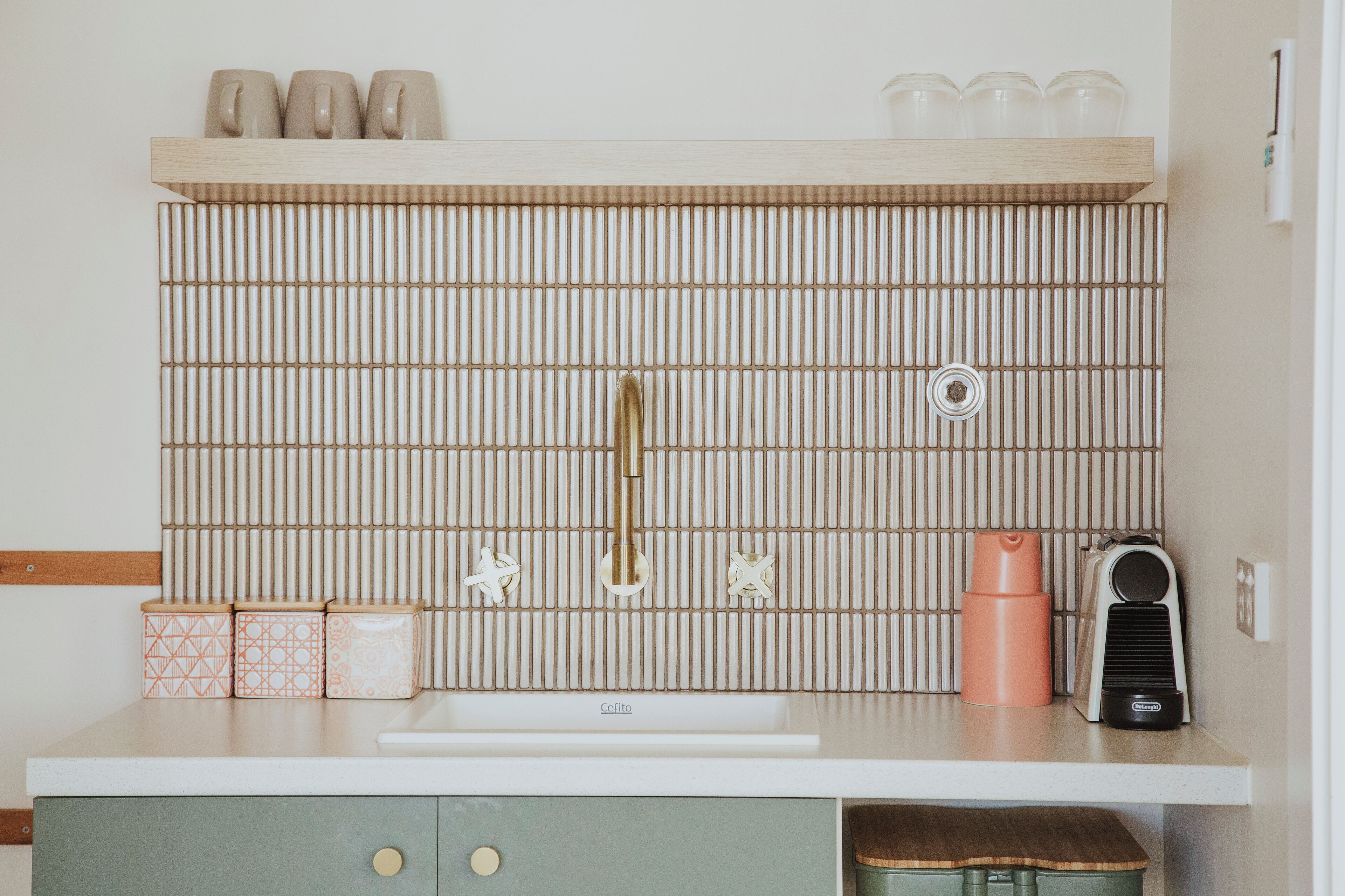 A kitchen with a white countertop, a sink, a coffee maker, and a toaster.
