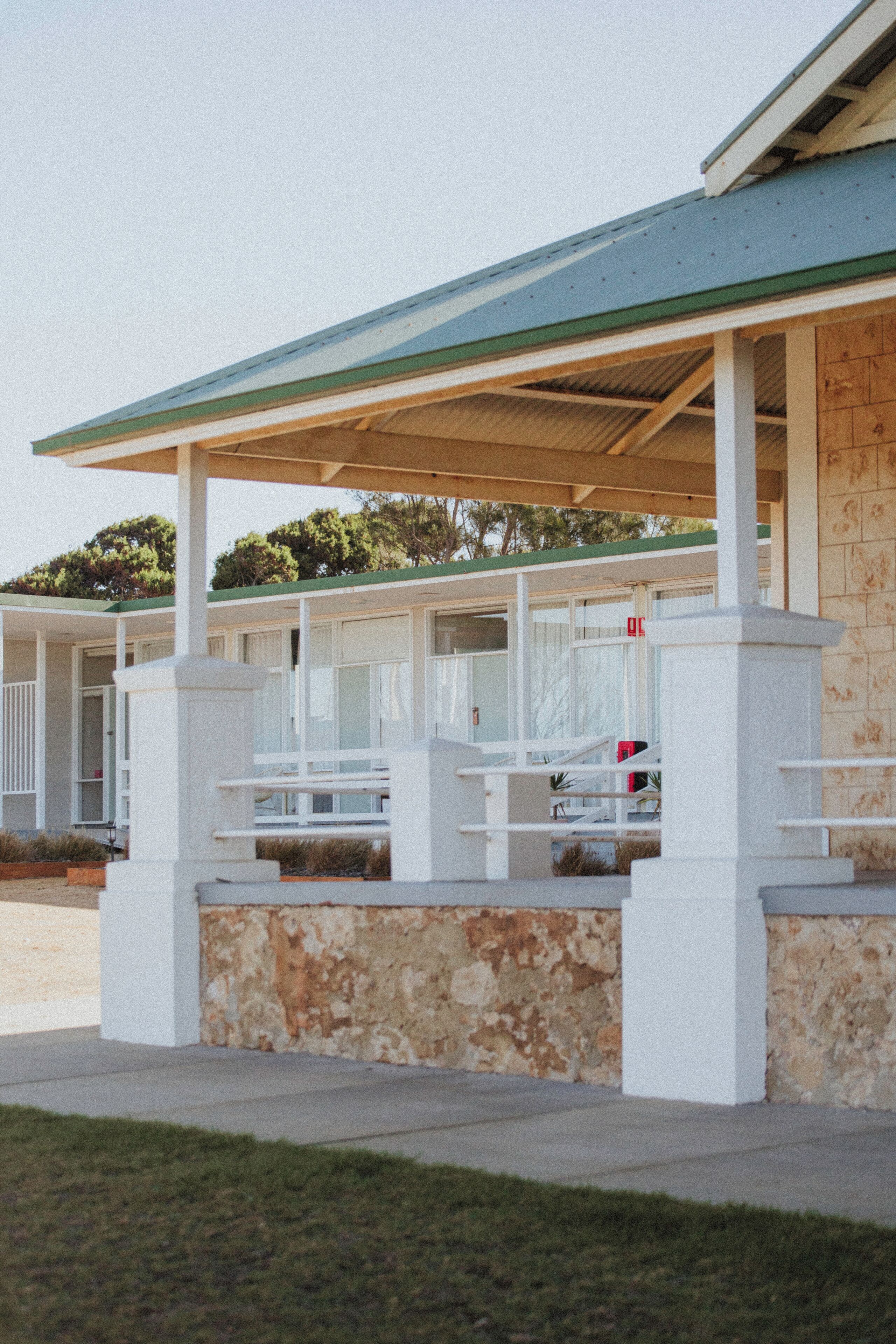 A motel with a covered outdoor seating area and a stone facade.