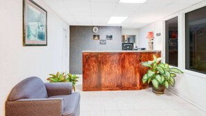 Een receptiegedeelte met een houten balie, een ingelijst kunstwerk aan de muur en een potplant.