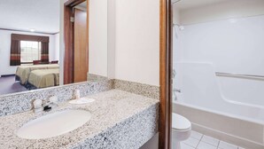 Een badkamer met een granieten aanrechtblad, een wastafel, toilet en een bad.