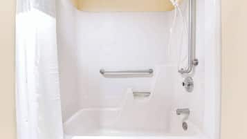 A white bathtub with a handheld showerhead and grab bars.