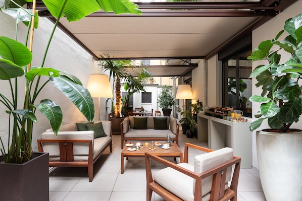 A cozy outdoor seating area with wooden furniture, potted plants, and ambient lighting. - Hotel Cristoforo Colombo – Preferred Hotels & Resorts (Milan)