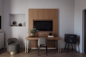 A modern room with a wooden desk, a television, two chairs, and a small side table. - Hotel Cristoforo Colombo – Preferred Hotels & Resorts (Milan)