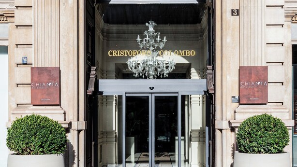 A grand entrance with an arched doorway, a chandelier, and two potted plants. - Hotel Cristoforo Colombo – Preferred Hotels & Resorts (Milan)