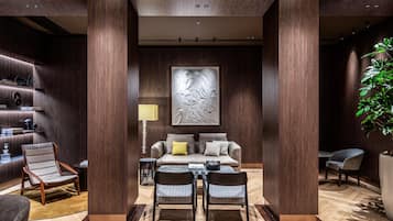 Un interior moderno con una zona de estar central, una estantería y una pieza decorativa en la pared.