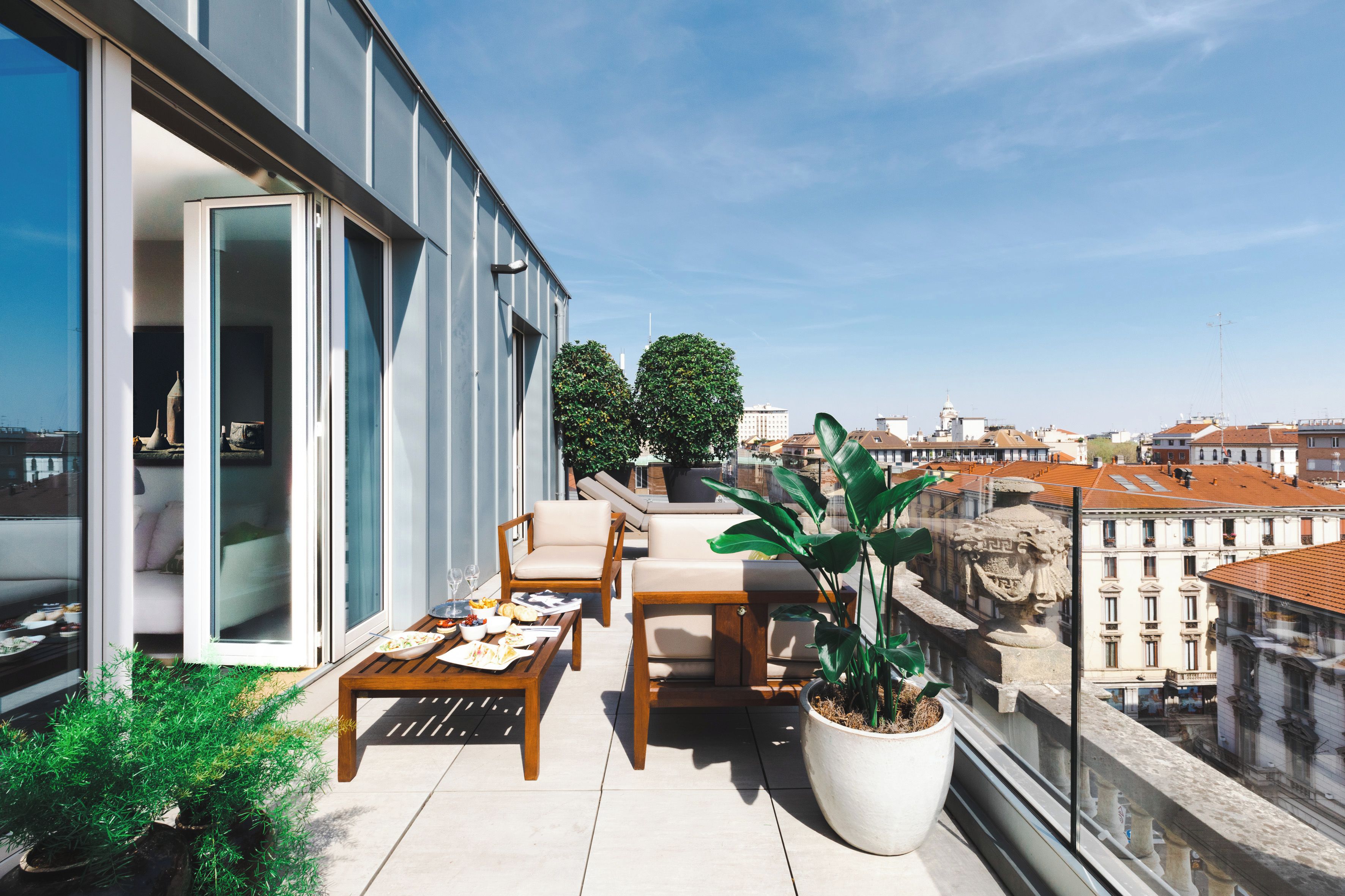 A balcony with a dining table and chairs, a potted plant, and a view of the cityscape.