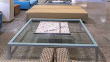 Un hall d’entrée moderne avec une table basse en verre, des sièges à motifs et un canapé bleu.