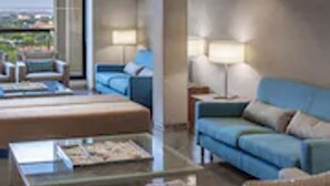 A modern living room with a glass coffee table, a sofa, and a chair. - Gran Hotel Rey Don Jaime (Castelldefels)