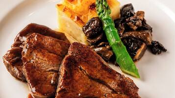 Un plato con bistec, champiñones, espárragos y puré de papas.