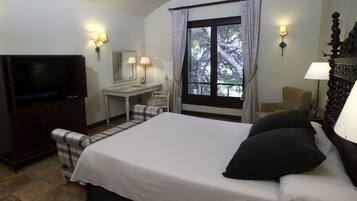 A hotel room with a bed, a desk, a chair, a television, and a window with curtains.