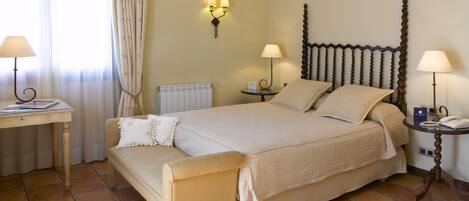A neatly arranged hotel room with a large bed, bedside tables, a desk, and a chair.