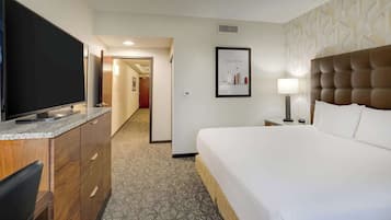 A hotel room with a bed, a TV, a desk, and a bathroom.