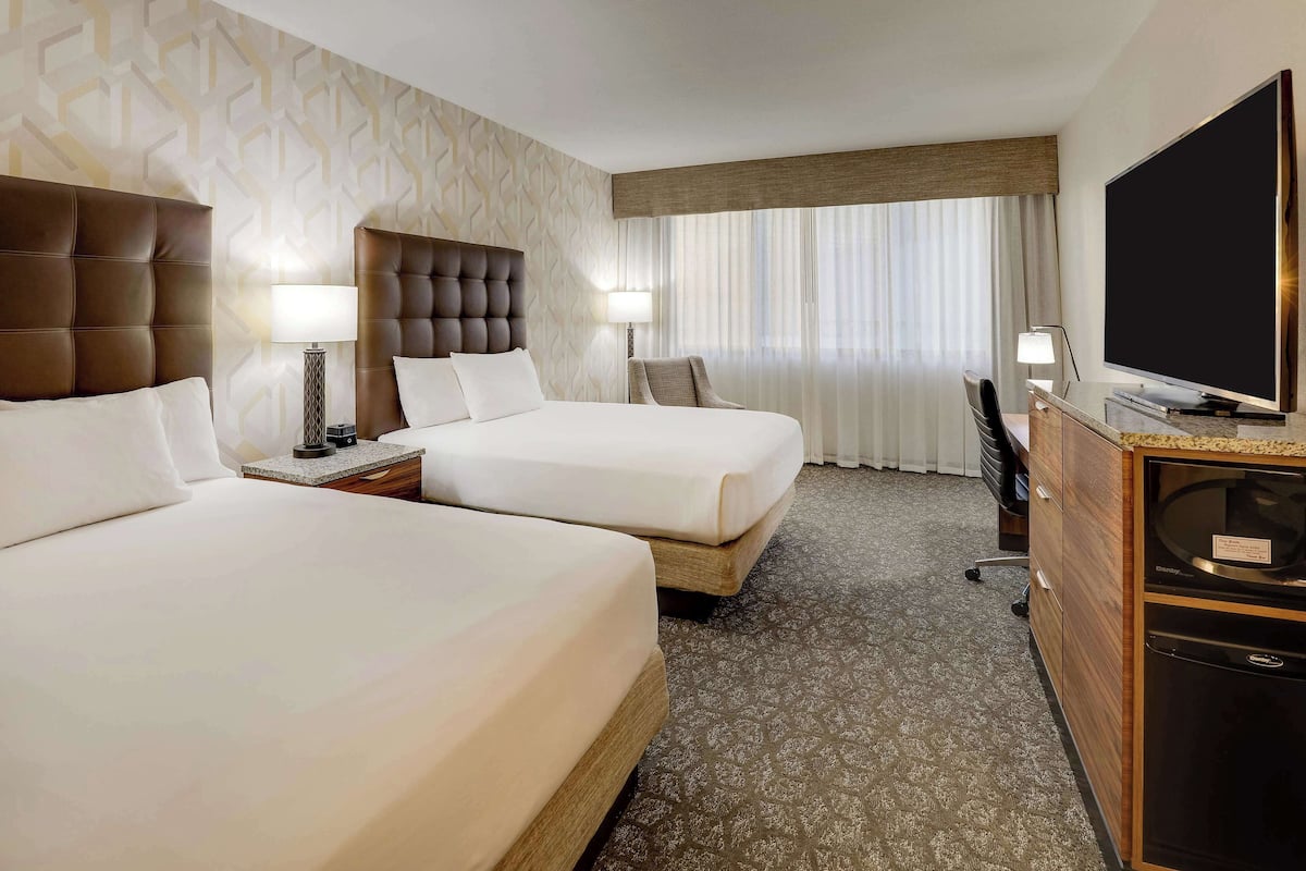 Une chambre d’hôtel avec deux lits, une télévision, un bureau et un minibar.
