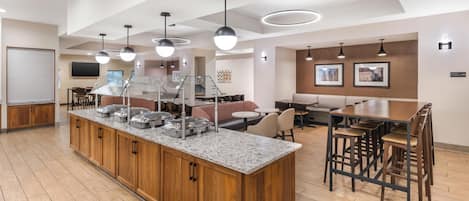 Una cocina moderna con encimeras de granito, armarios de madera y una isla central con equipamiento para servicios de alimentación.