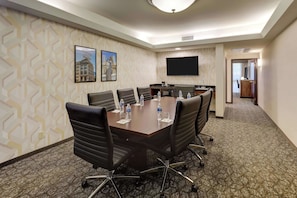 A conference room with a large table, four chairs, water bottles, and a flat-screen TV. - Drury Plaza Hotel Columbus Downtown (Columbus)