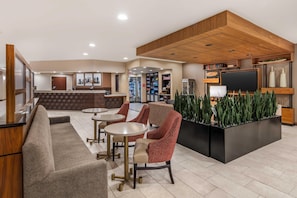 Un hall de hotel con mostrador de recepción, zona de estar y televisor.