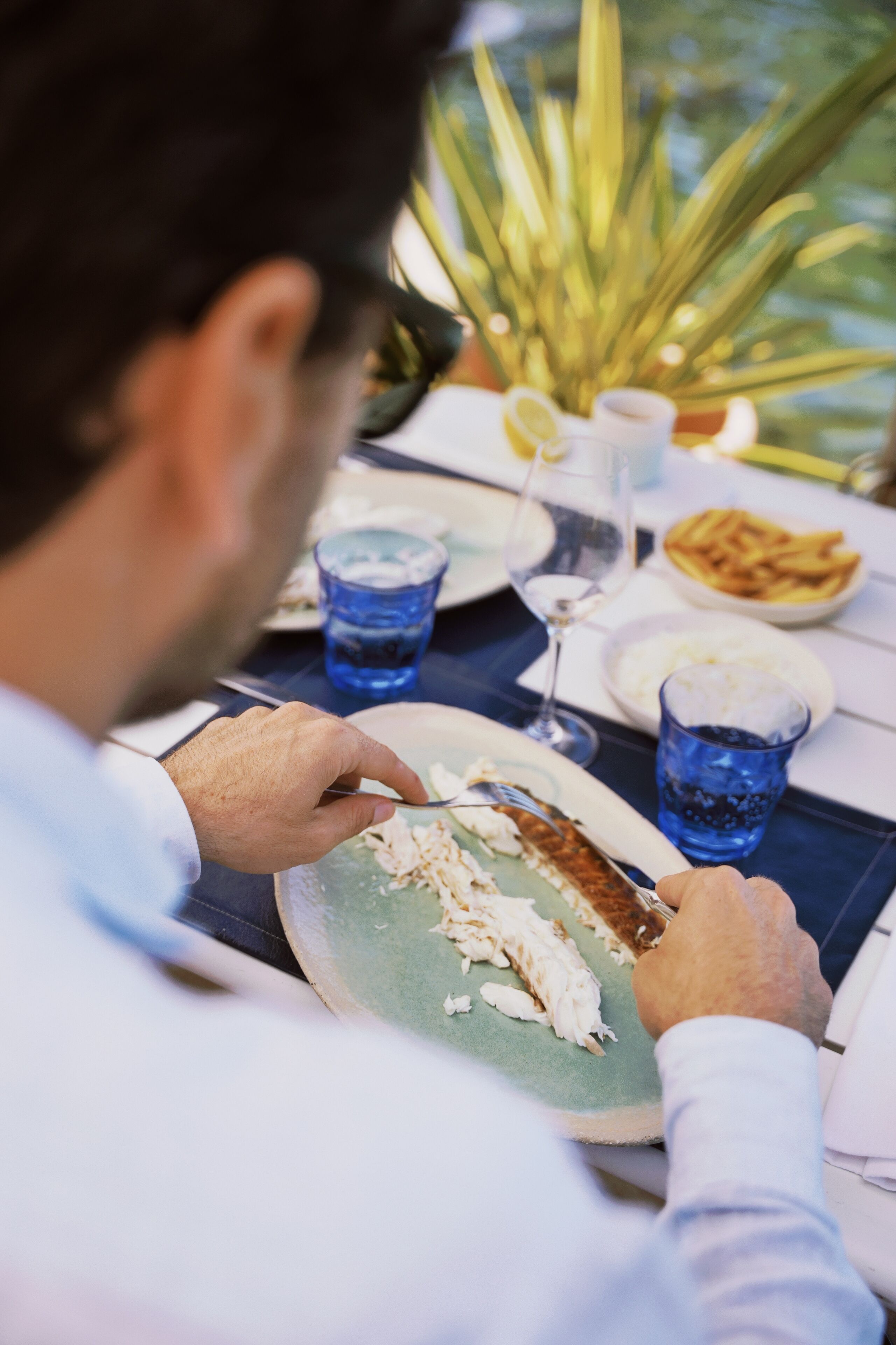 A person dining at a table with a plate of food, a glass of water, and a glass of a beverage.