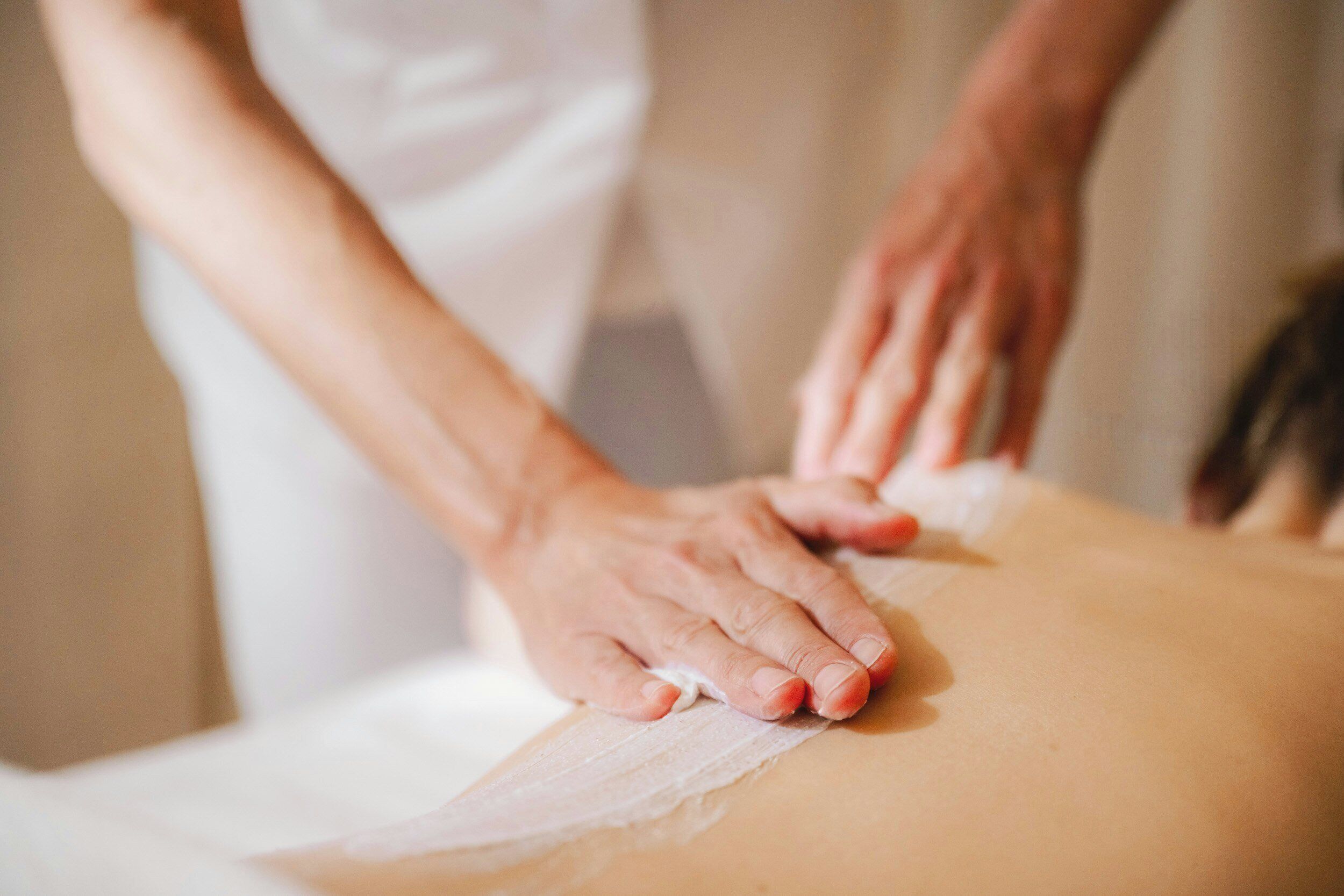 Et nærbillede af hænder, der giver en massage på en persons ryg.