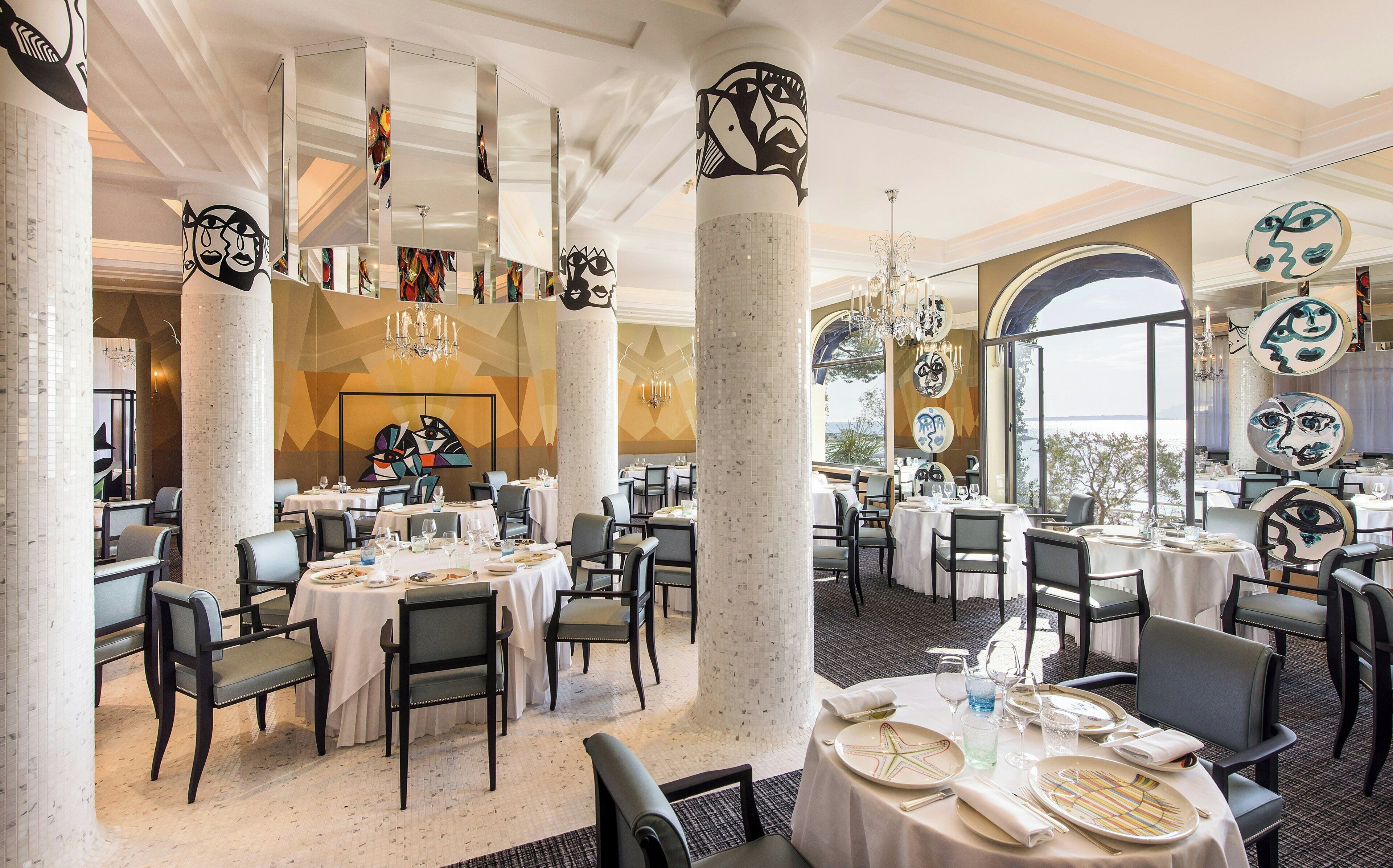 Ein Restaurant mit runden Tischen, Stühlen und Meerblick.
