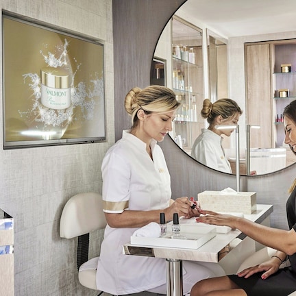 A salon interior with a reception desk, a large mirror, and shelves with various products.