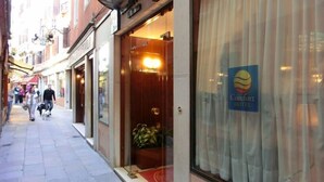 A hotel entrance with a sign for Comfort Hotel, a glass door, and a red carpet leading inside. - Hotel Diana (Venice)