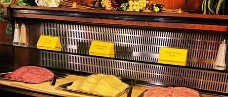 A deli counter with various meats, cheeses, and condiments.