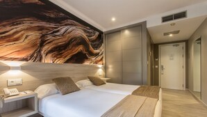A modern hotel room with a large bed, bedside lamps, a phone on the nightstand, and a marble-like wall mural.