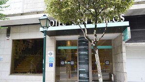 A hotel entrance with a modern facade, a glass door, and a sign welcoming guests.