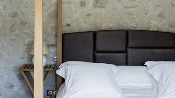 Un dormitorio con cabecera de madera, cama con ropa de cama blanca y pared con estampado de piedra.