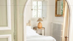 A bedroom with a bed, a lamp, a chair, and a radiator.