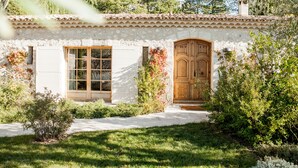 A rustic stone house with a tiled roof, a wooden front door, and a window with a wooden frame.