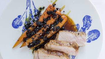 A plate with sliced meat and vegetables, possibly carrots, on a white plate with blue floral patterns.