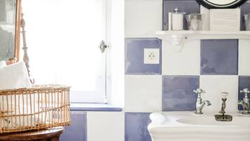 A bathroom with a checkered tile backsplash, a white sink, a wooden chair, and a mirror.