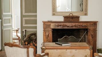 Una habitación con chimenea, un espejo y una silla.