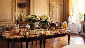 A breakfast buffet with various food items, a vase with flowers, and a chandelier.