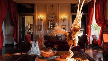 A room with a large bird sculpture, ornate wall decorations, and a chandelier.