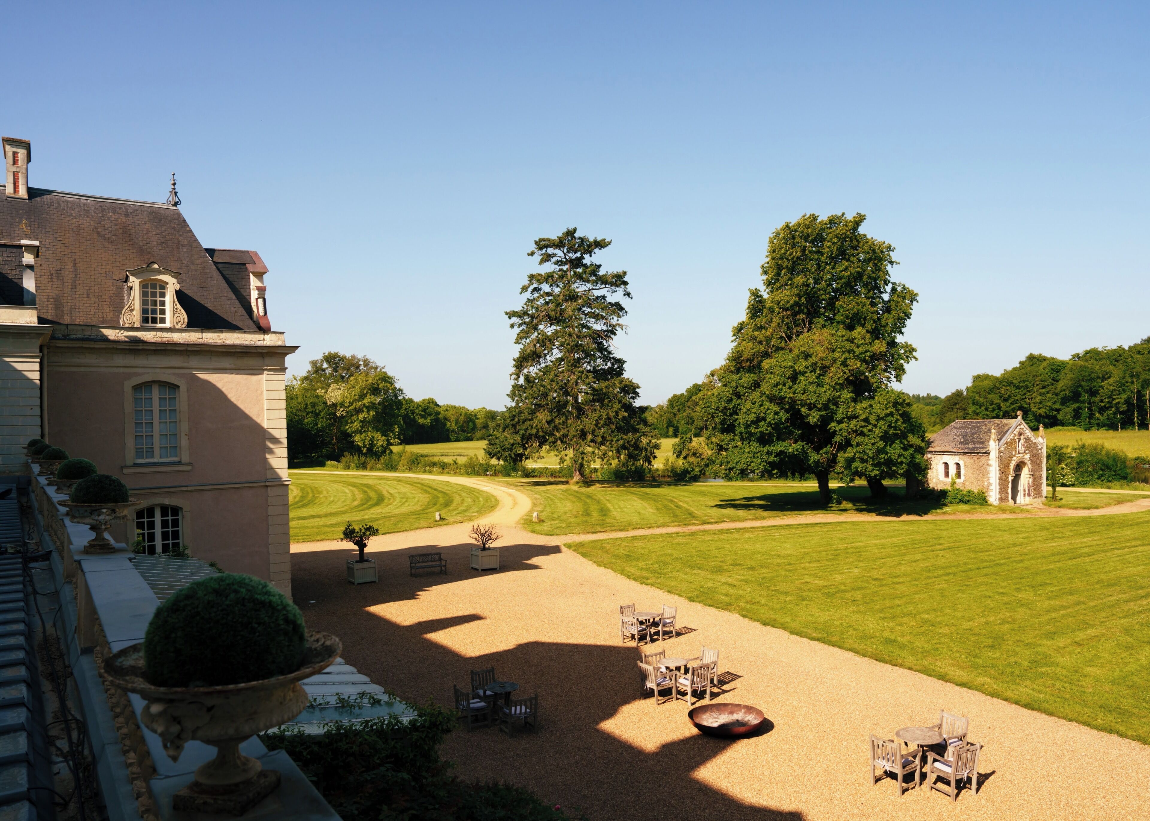 A large building with a lawn, outdoor seating, and a small structure.