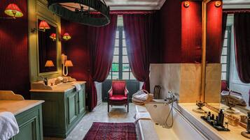 Um banheiro luxuoso com uma banheira grande, uma toucador com espelho e uma cadeira vermelha.